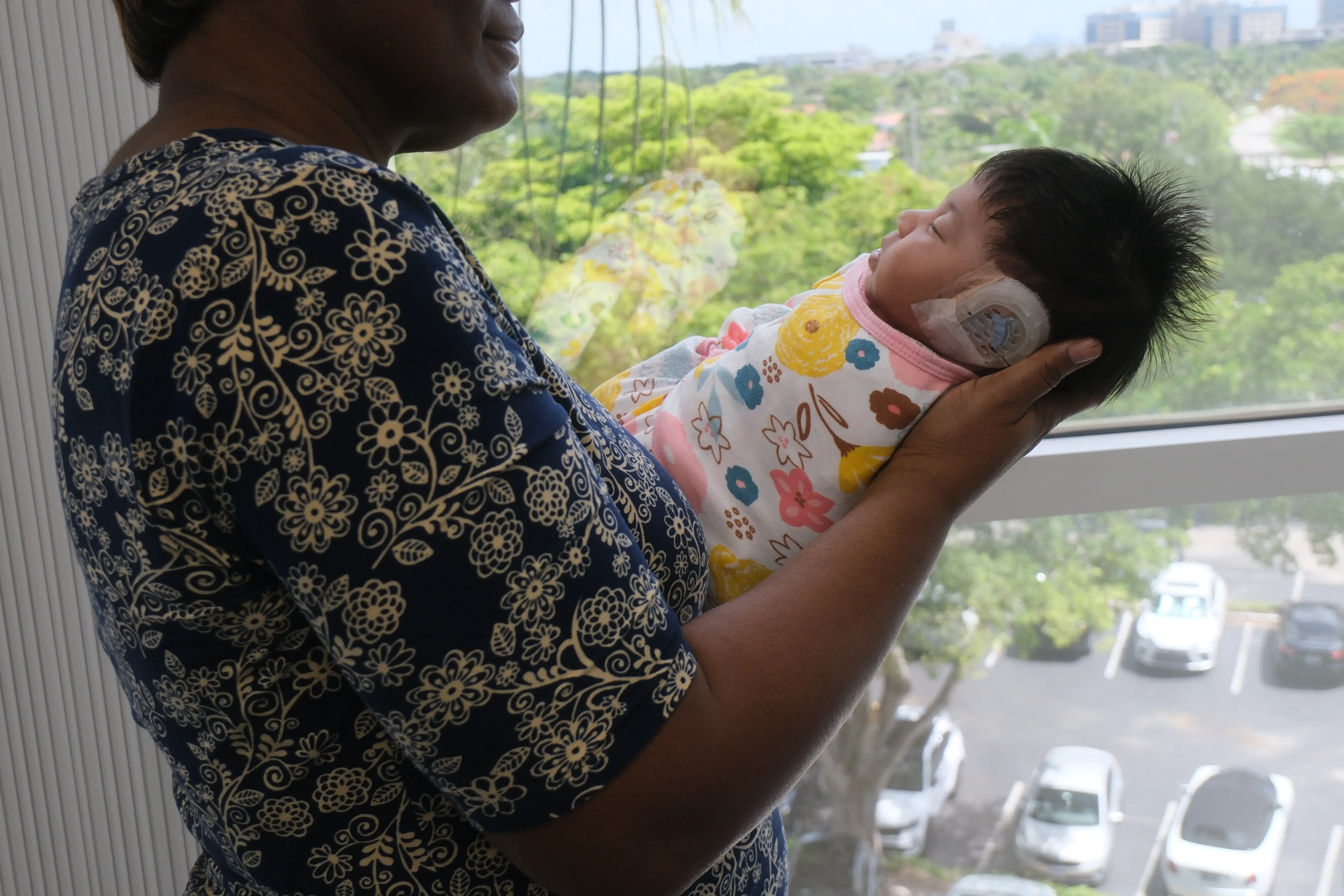 Mother holding baby with EarWell device