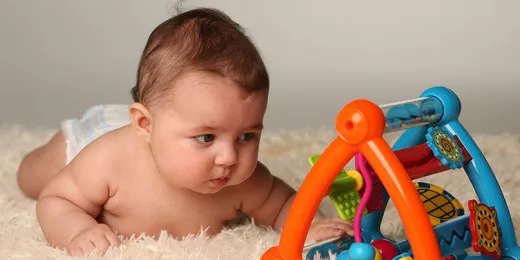 baby lying on tummy playing with a toy